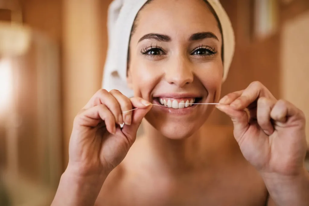 Persona utilizando hilo dental como parte de su rutina de higiene oral